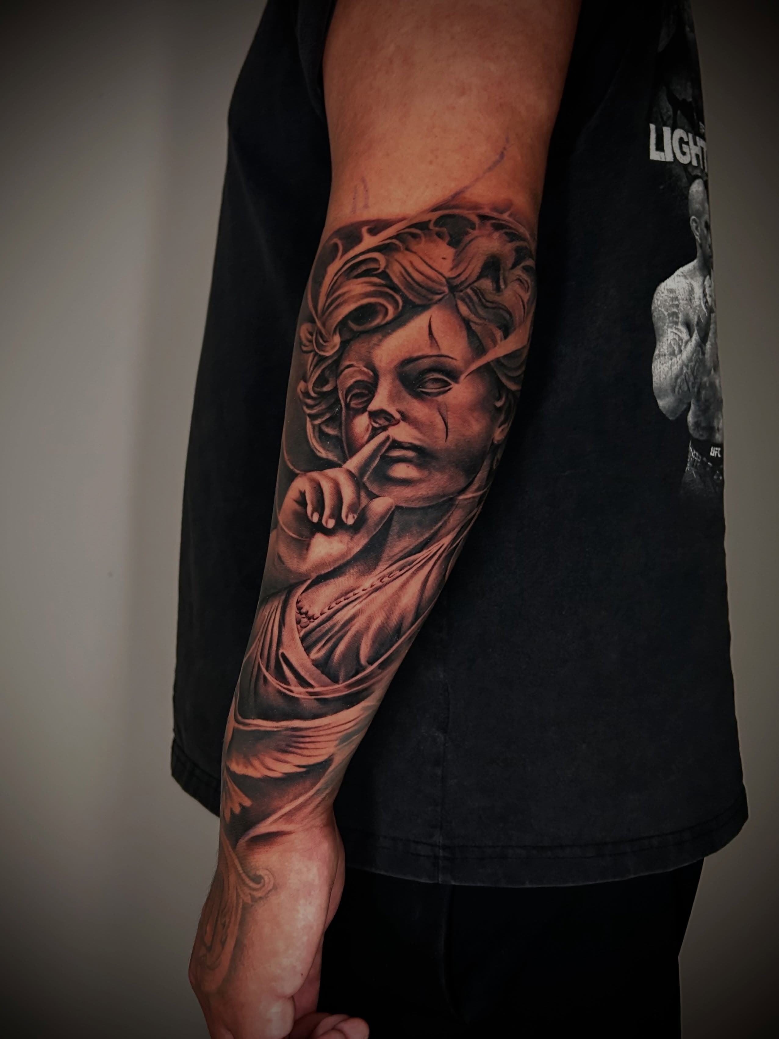 Forearm sleeve in black and grey — a classical face with a finger raised to her lips
