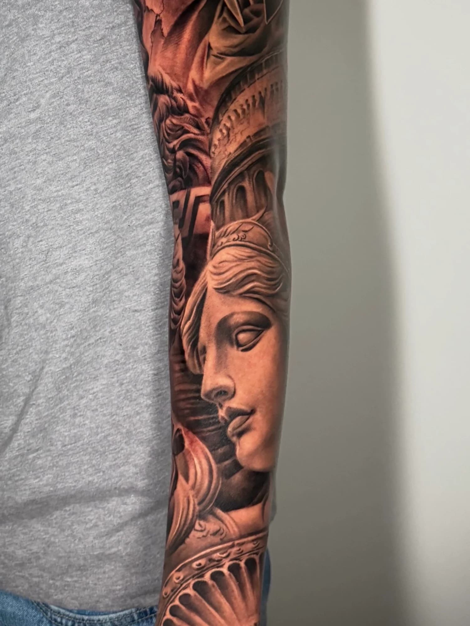 Black and grey tattoo: classical portrait, ornamental details, and architecture.