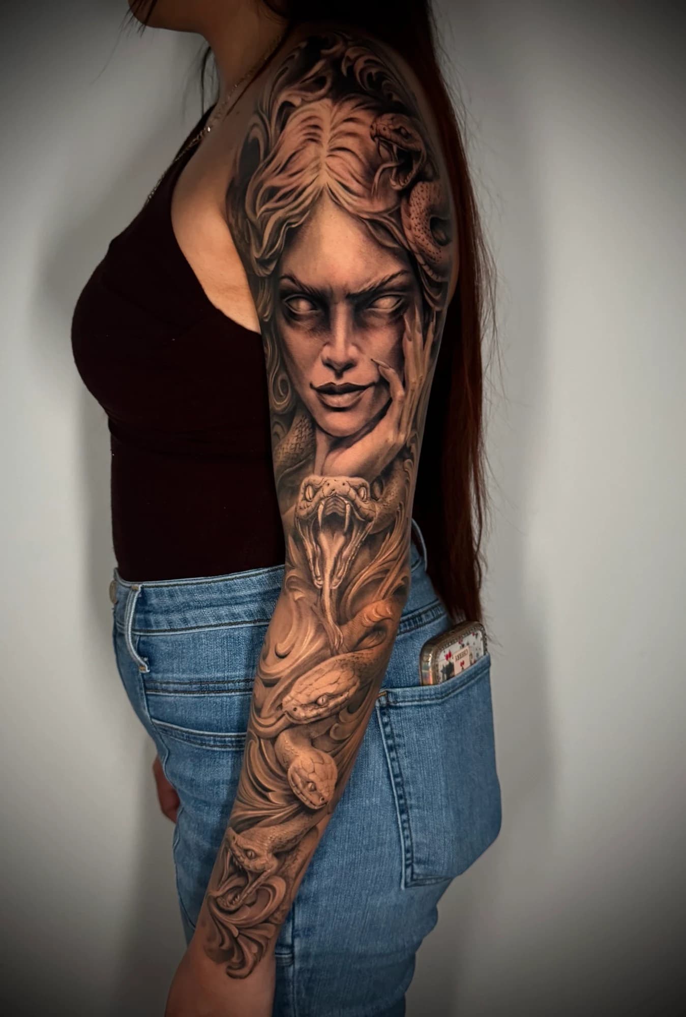 Black and grey tattoo: medusa portrait and snakes flowing down the arm.