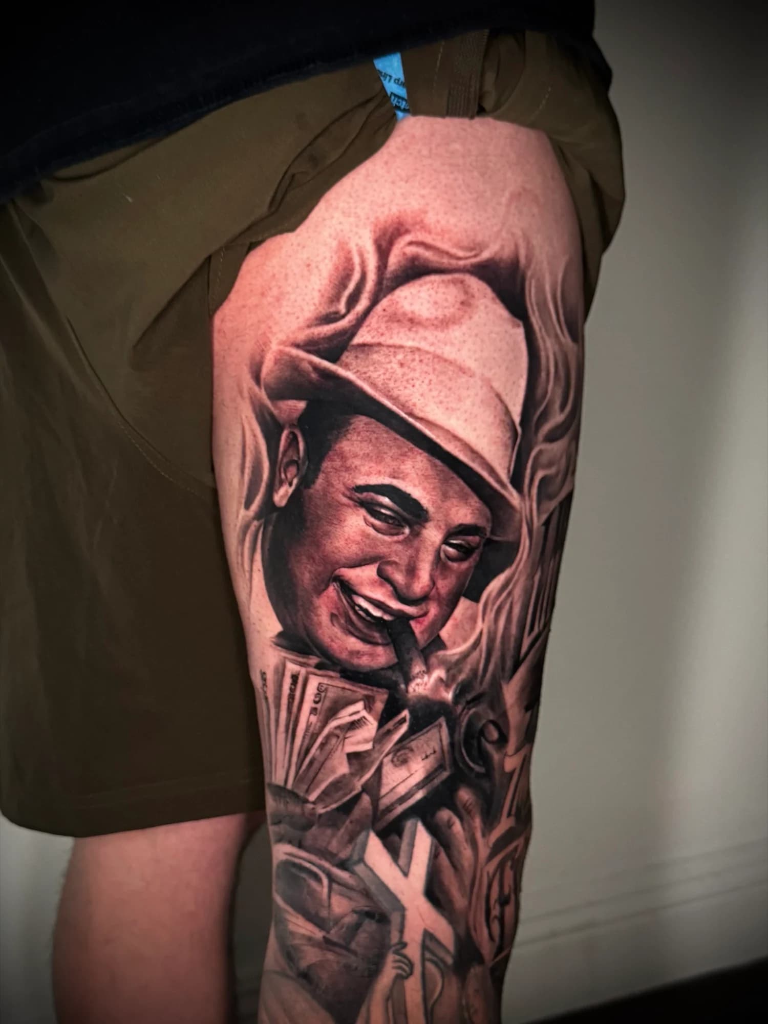 Black and grey tattoo: smiling portrait with a tall hat and detailed shading.