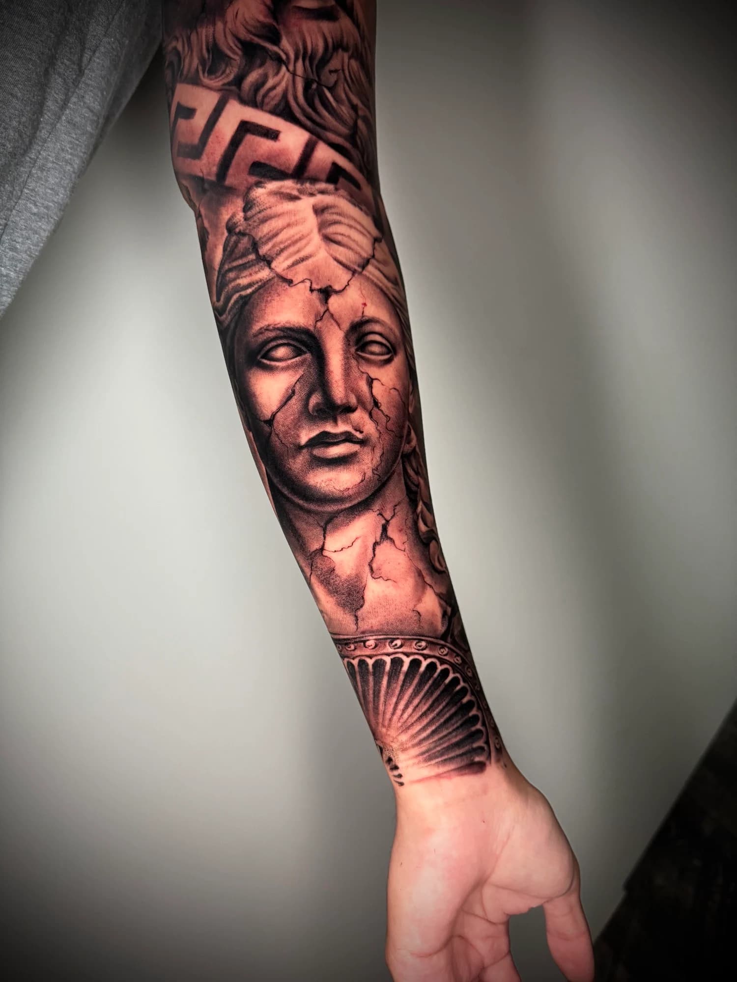 Black and grey tattoo: classical portrait framed by architectural patterns.