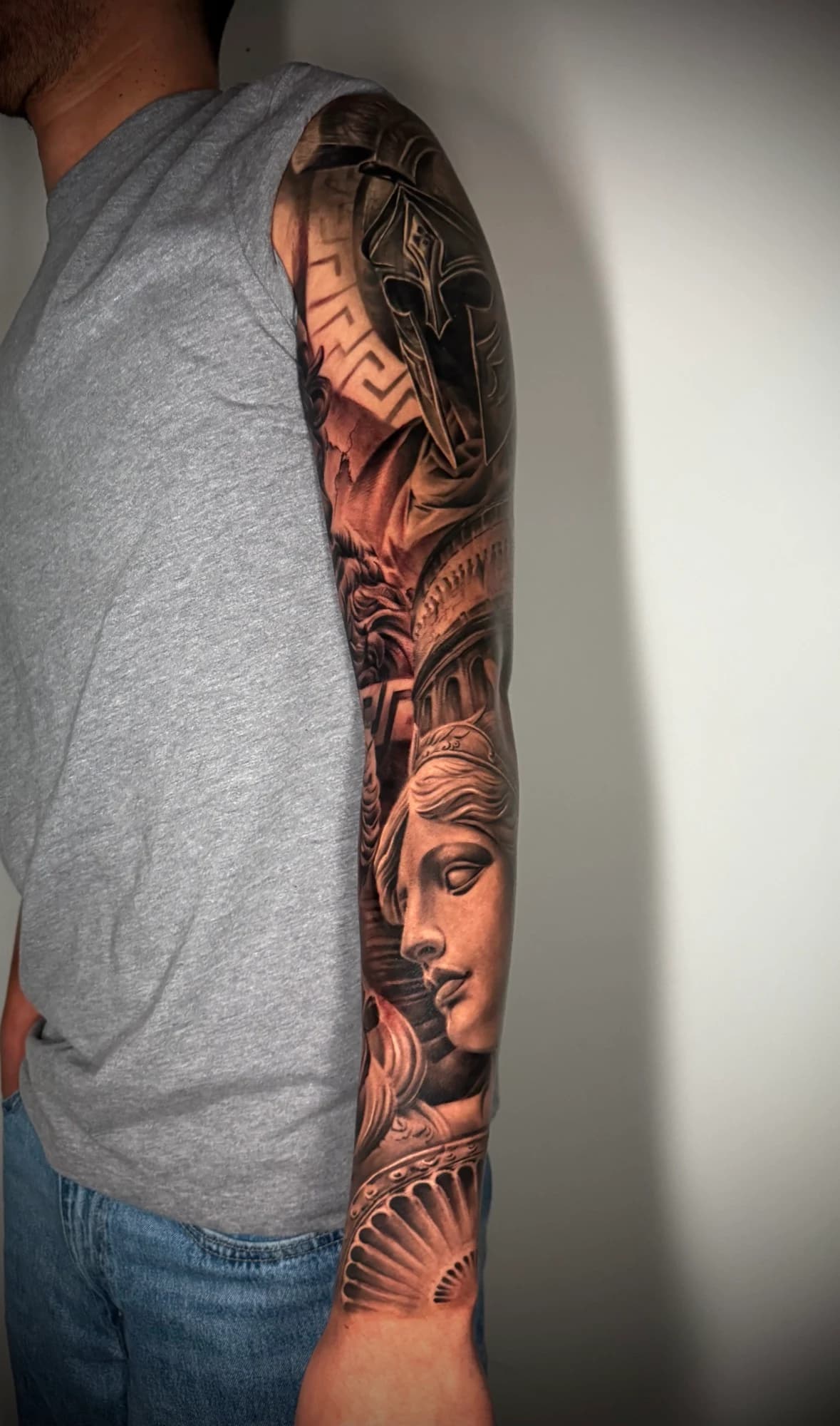 Black and grey tattoo: classical portraits and architectural details along the arm.