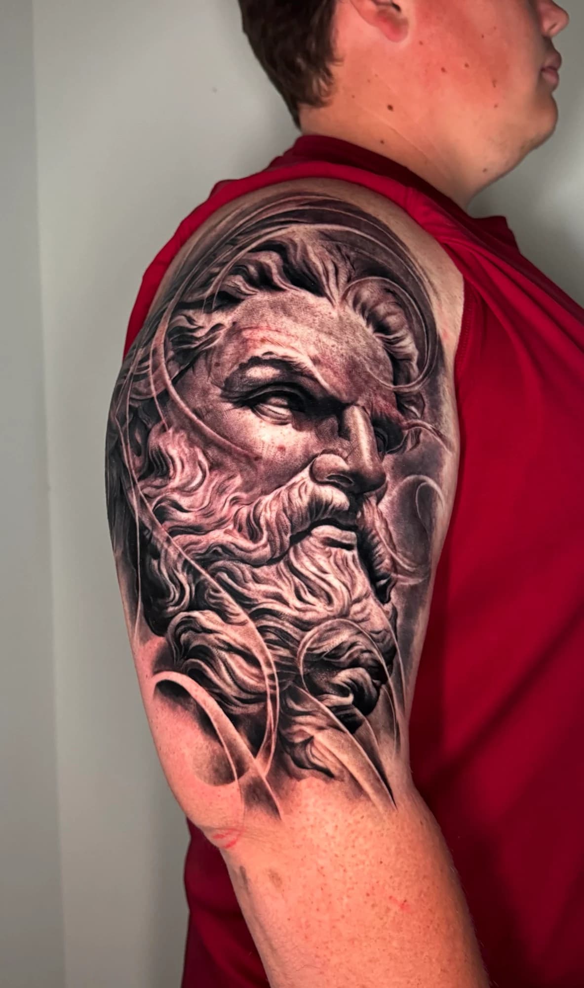 Black and grey tattoo: bearded classical portrait with flowing hair and deep shading.