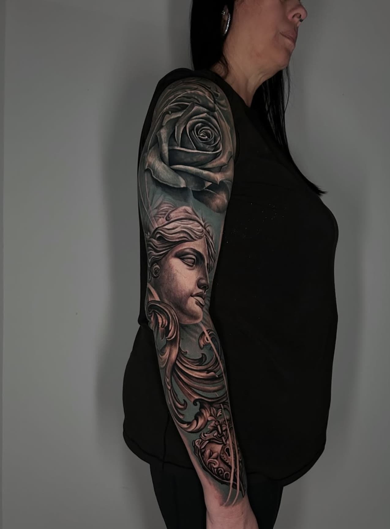 Full sleeve in black and grey — a rose above a classical statue face