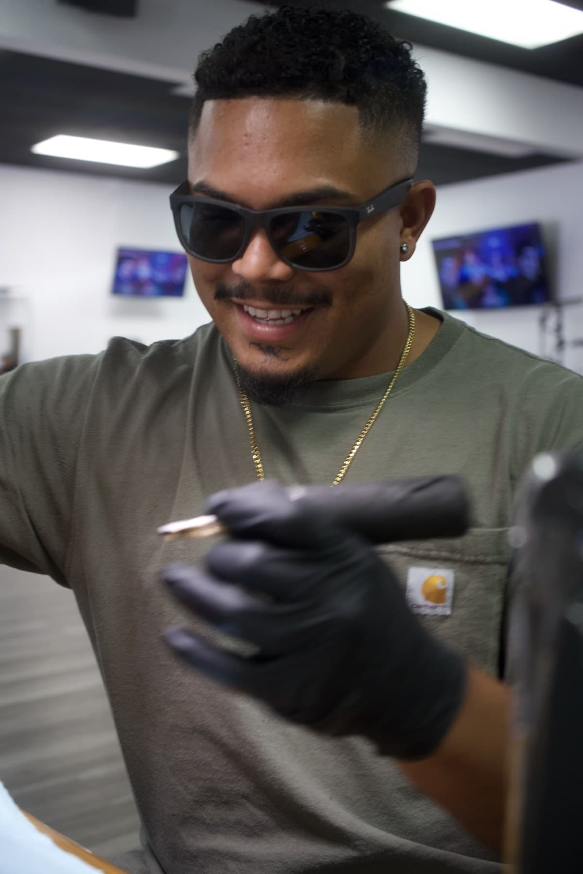 Roly smiling mid-session, tattoo machine in hand at Iconiq Tattoo Studio