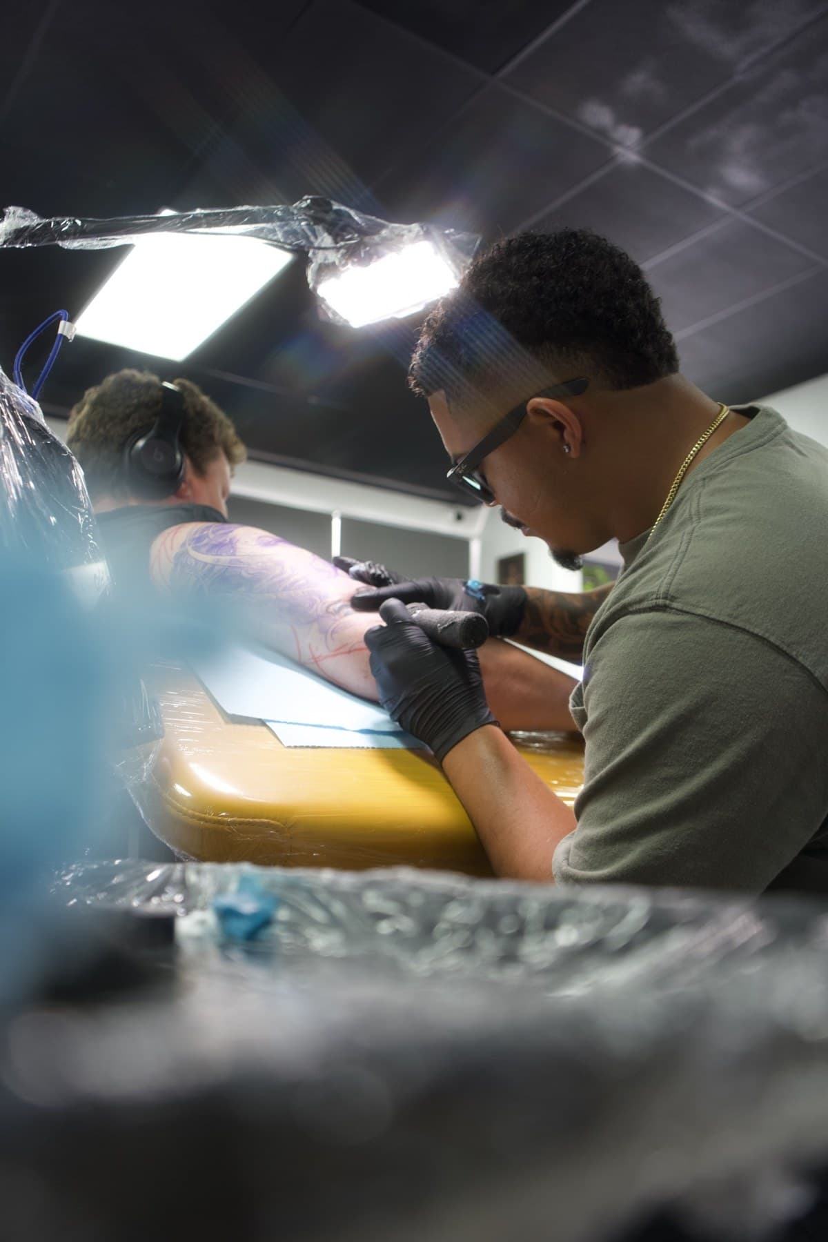 Roly tattooing a large black and grey forearm piece at Iconiq Tattoo Studio